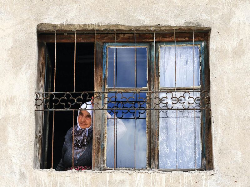 Person calmly looking at a distant object through a window.